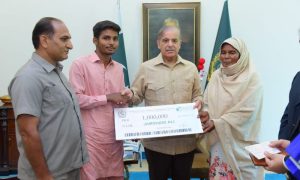 Prime Minister Muhammad Shehbaz Sharif presenting a cheque of 1 million rupees to Jamshed Ali