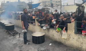 Palestinians Wait with Containers for Food Distribution in Rafah